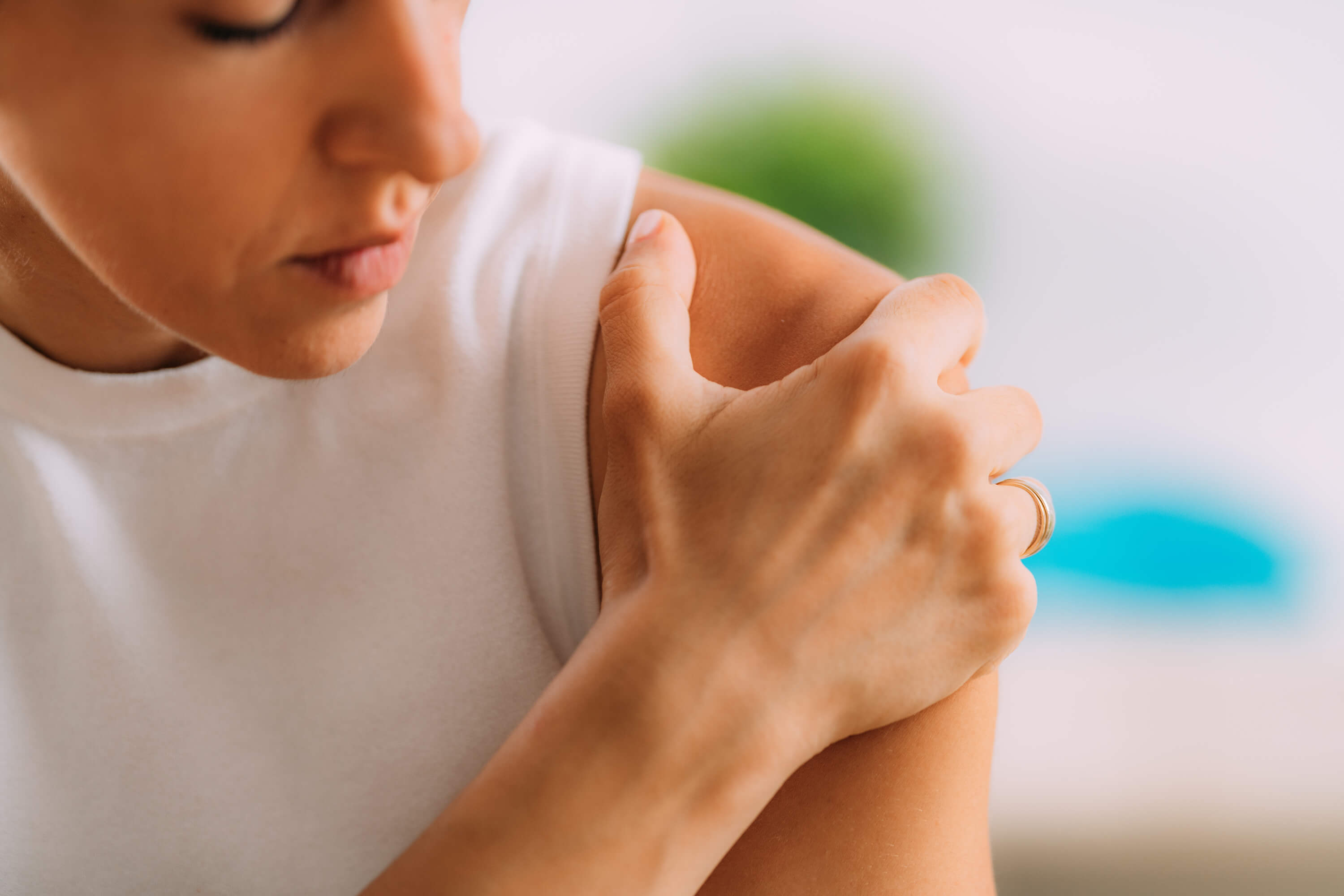 woman looking down and holding her shoulder with her hand 