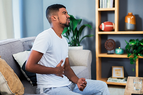 A man sitting down and holding his stomach in pain