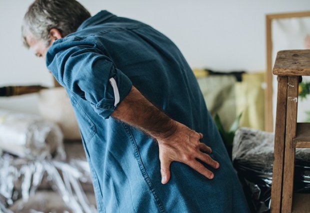 An older person holding their back in pain