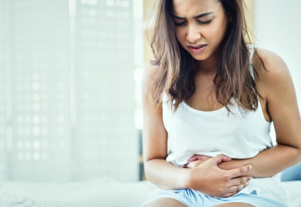 Young woman holding her stomach in pain